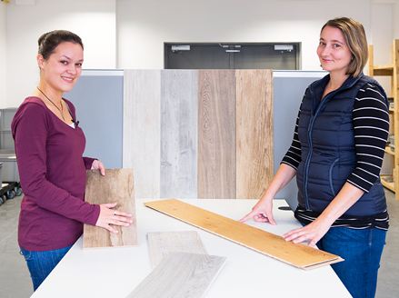 Dva zaměstnanci předvádějí různé dlaždice s dřevěným vzhledem