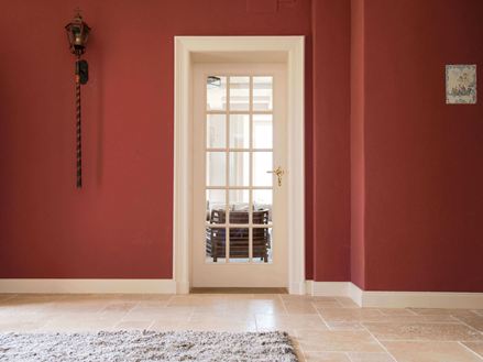 Vstupní prostor s travertinovými dlaždicemi a červenými stěnami