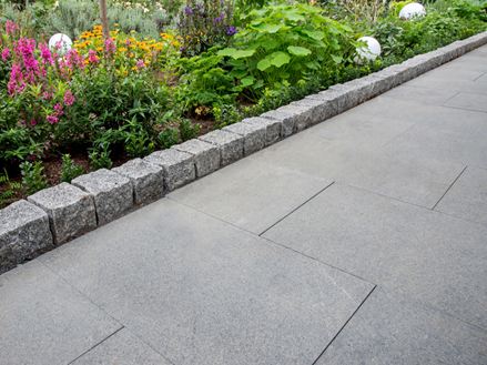 Stezka s žulovou deskou Padang Dark a sousední květinový záhon