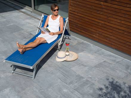 Žena relaxuje na zahradním lehátku a modrokamenných deskách Azur