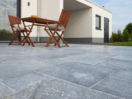 Pohled z žabí perspektivy na terasu s mramorovými deskami a dřevěným nábytkem