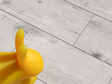 Pohled shora na panel s efektem dřeva Amber Oak se žlutým gumovým králíčkem