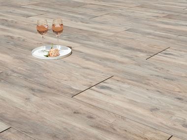 Dvě sklenice na víno a květina na terasových dlaždicích s efektem dřeva