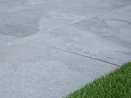 Terasové desky Alpine Grey ve vzhledu světlé břidlice s okrajem trávníku