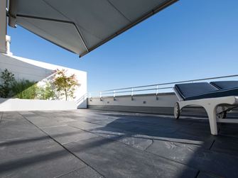 Střešní terasa s břidlicovou podlahou a lehátky na okraji z žabí perspektivy