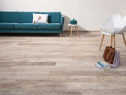 Obývací pokoj s Dlaždicemi Indie Sky s efektem dřeva, bílým křeslem a tmavě zelenou pohovkou