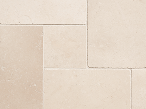 Detailní záběr na béžové vápencové dlaždice s úzkou spárou