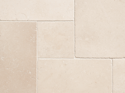 Detailní záběr na béžové vápencové dlaždice s úzkou spárou