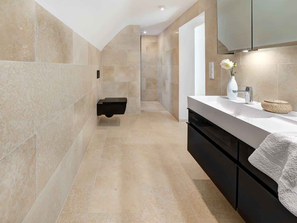 Světlý vápenec působí harmonicky i na velkých plochách! Koupelna s moderním nábytkem a vápencovými obklady Cleopatra Light na podlaze a stěnách