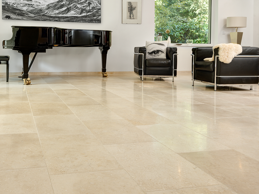 Světlý obývací pokoj s béžovou vápencovou podlahou, moderním sedacím nábytkem a klavírem