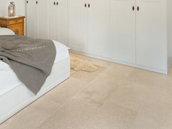Ložnice s bílou skříní a bílou postelí, béžová vápencová dlažba na podlaze