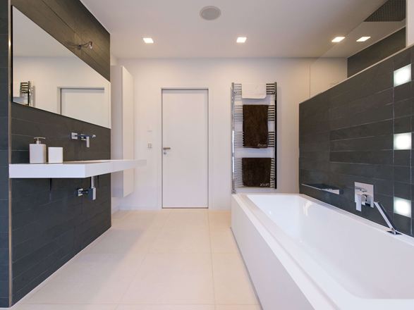 Moderní koupelna se světlými vápencovými dlaždicemi na podlaze a tmavou břidlicí na stěnách