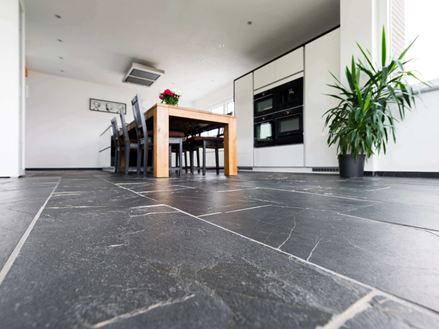 Žabí perspektiva na Black Rustic břidlicové podlaze s dřevěným jídelním stolem a rostlinou v pozadí