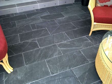 Proutěný nábytek s červenými polštáři na tmavě černém Black Rustic břidlicové dlaždice s bílými spárami