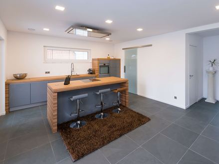 Kuchyně s dřevěnými prvky a břidlicovými dlaždicemi v jemné šedé barvě jako podlaha