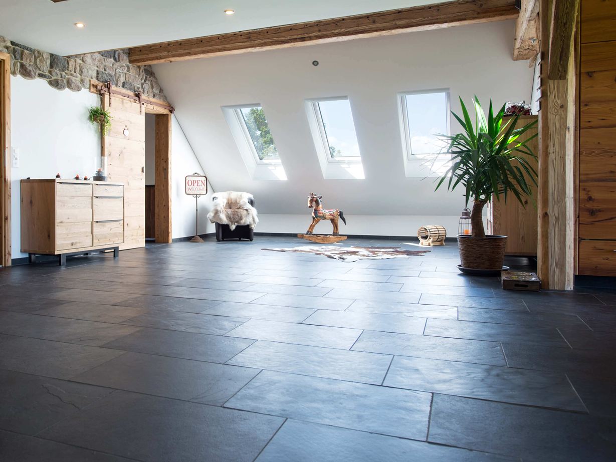 Pokoj s antracitovou břidlicovou podlahou a dřevěným nábytkem, bílé stěny