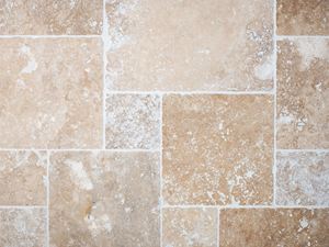 Pohled z ptačí perspektivy na položenou a spárovanou travertinovou dlažbu v béžové a hnědé barvě