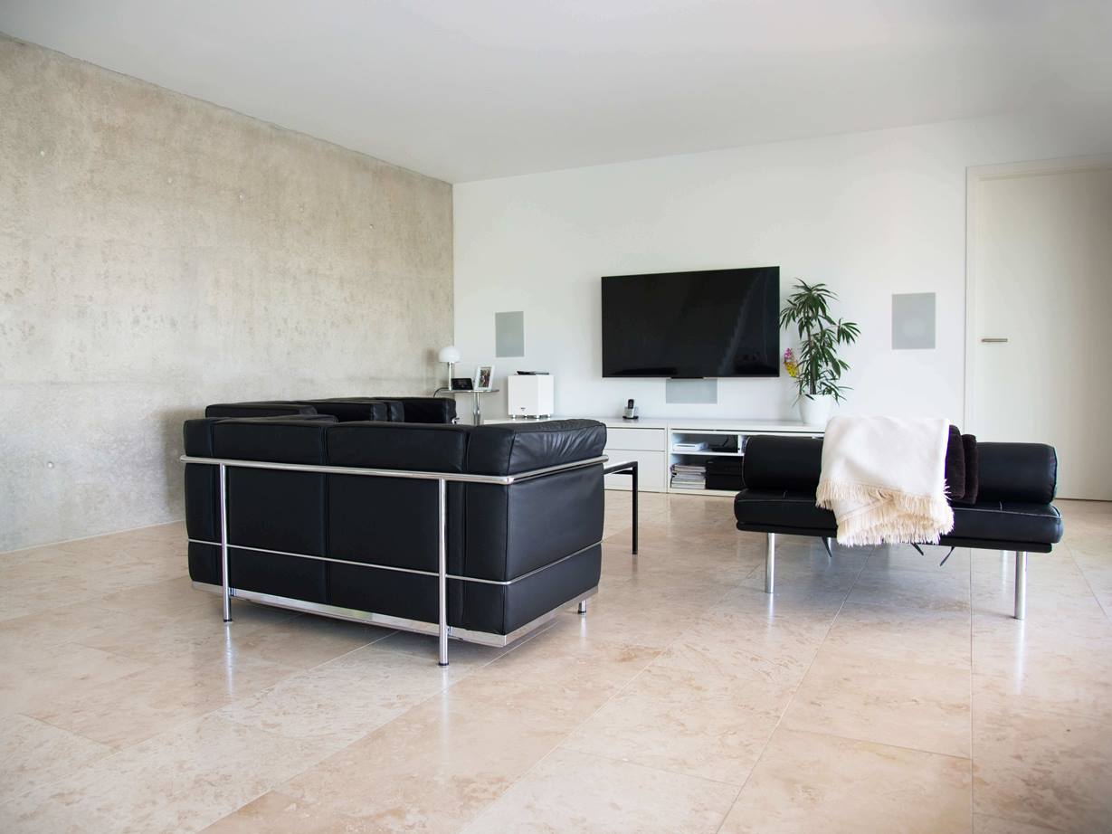 Travertin Classic Light: jednoduchý a elegantní Moderní obývací pokoj s černou sedací soupravou a světle béžovou travertinovou dlažbou Classic Light jako podlahou