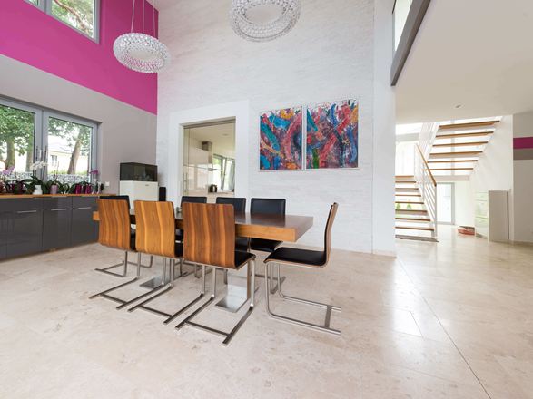 Otevřený jídelní kout s moderními dřevěnými židlemi a barevnou malbou na stěně, podlaha ze světlých travertinových dlaždic s leštěným povrchem.