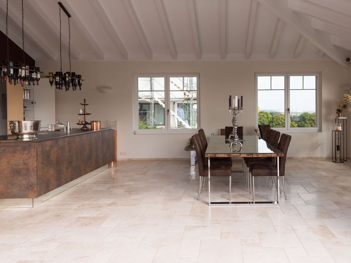 Travertinové obklady v římské vazbě v moderní kuchyni s jídelním stolem a kuchyňským ostrůvkem