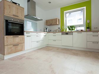 Kuchyňská linka v bílé barvě s dřevěnými prvky a zeleným okenním rámem na Light travertinovém obkladu s tromlovaným, nezarovnaným povrchem