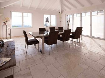 Jídelna s vysokým stropem, stolem a židlemi na travertinu Light v římské vazbě