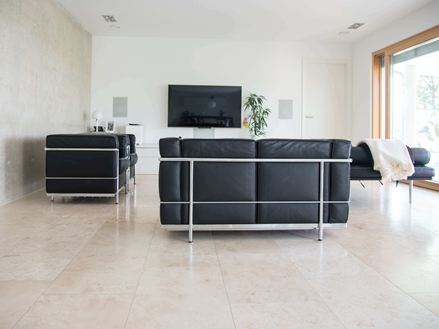 Obývací pokoj s dlaždicemi Travertin Classic Light a moderní černou pohovkou