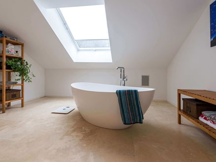 Koupelna s travertinem Medium Line, volně stojící vanou a ručníkem