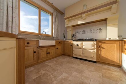 Dřevěná kuchyňská linka se středně velkou travertinovou dlažbou, tromlovaná