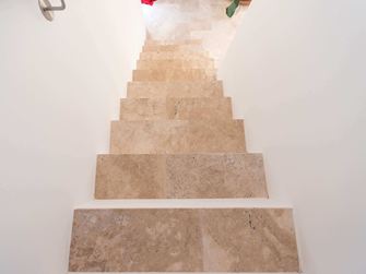 Schodiště s bílými stěnami a travertinovým médiem jako nášlapnými deskami