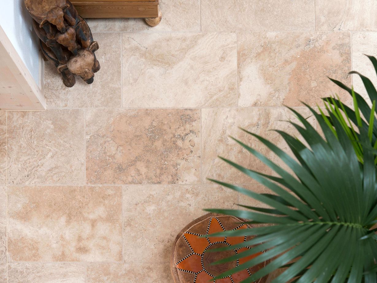 Dlaždice Rustic Travertine: s typickou, okouzlující strukturou pórů Pohled z ptačí perspektivy na položenou travertinovou dlažbu Rustic s rostlinami a dřevěnými doplňky