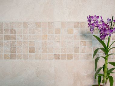 Orchidej před mozaikovou stěnou se světlým travertinem