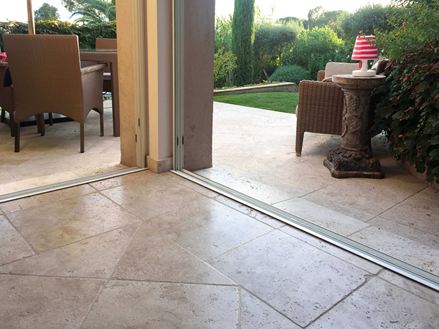 Přechod z interiéru do exteriéru s béžovo-hnědým travertinem