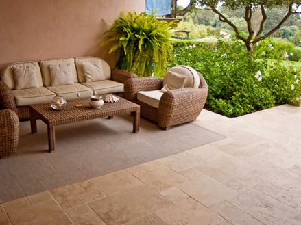 Vstupní prostor středomořského hotelu s proutěnými křesly, travertinovou podlahou a zelenou zahradou v pozadí