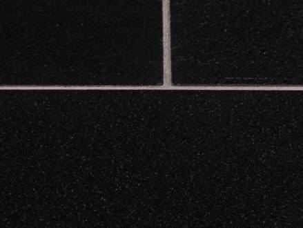 Detailní záběr tmavé žulové dlažby Nero Assoluto s bílými spárami