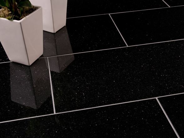 Dva bílé květinové lustry na tmavé žulové dlažbě Star Galaxy s úzkými světlými spárami.