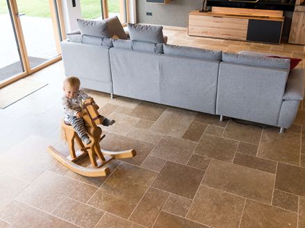 Dítě sedící na houpacím koni a hrající si v obývacím pokoji s podlahou Noce SELECT Travertine