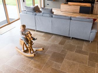 Dítě sedící na houpacím koni a hrající si v obývacím pokoji s podlahou Noce SELECT Travertine