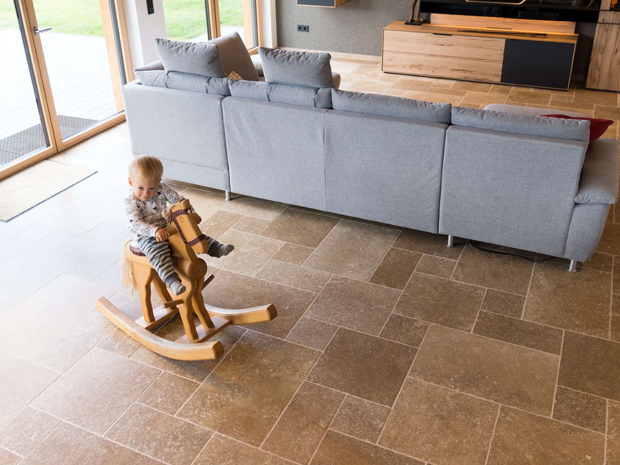 Dítě sedící na houpacím koni a hrající si v obývacím pokoji s podlahou Noce SELECT Travertine