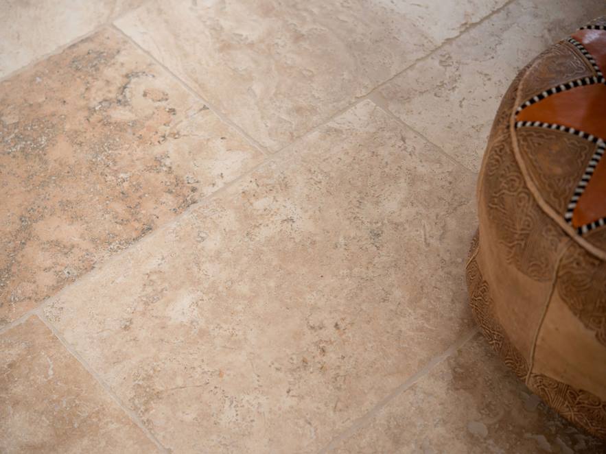Rustic travertinová dlažba položená v hnědé a béžové barvě s ozdobnými polštáři