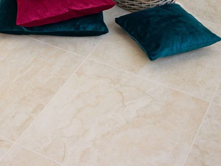 Barevné polštáře na jemných kamenných dlaždicích ve vzhledu světlého travertinu