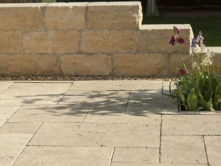 Travertinová deska Medium Select se stěnou z přírodního kamene a květinami v pozadí