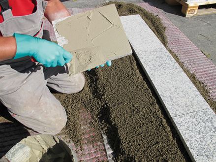 Montážní firma natře zadní stranu kamene lepidlem pro pokládku na štěrkovou podkladovou vrstvu.