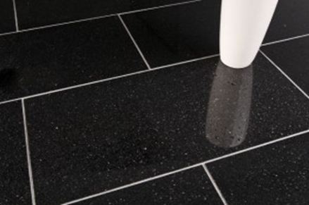 Bílá váza na černé žulové dlažbě se světlými spárami