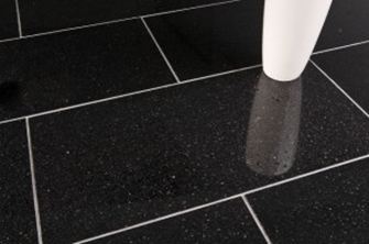 Bílá váza na černé žulové dlažbě se světlými spárami