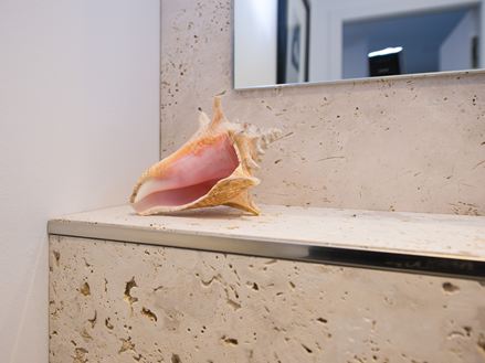 Travertinové obklady s dekorem mušlí v koupelně