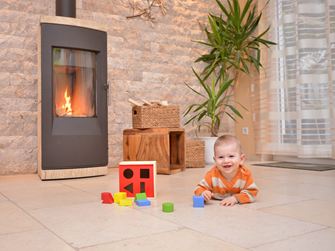 Dítě si hraje na podlaze z přírodního kamene před krbem