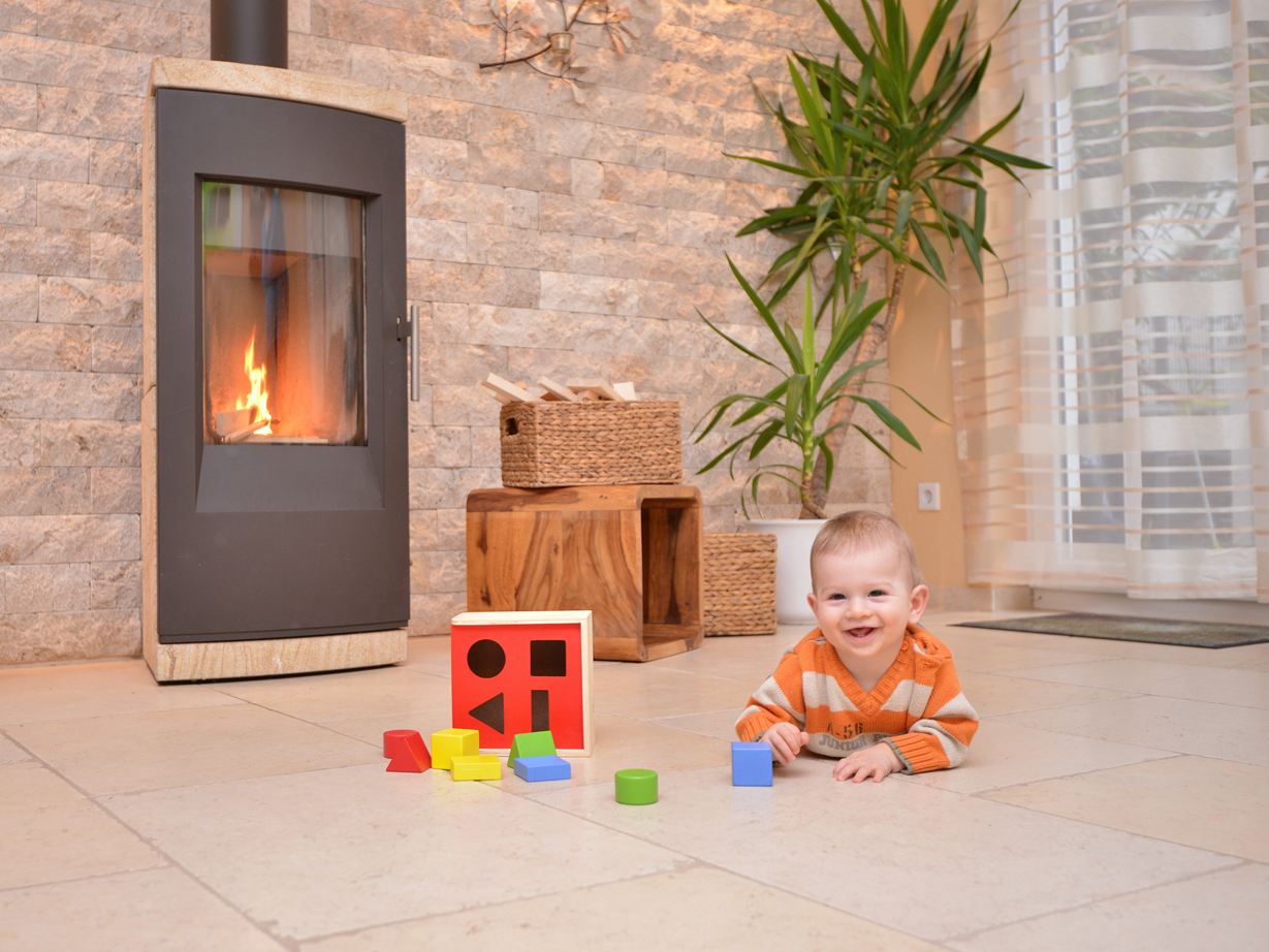 Dítě si hraje na podlaze z přírodního kamene před krbem