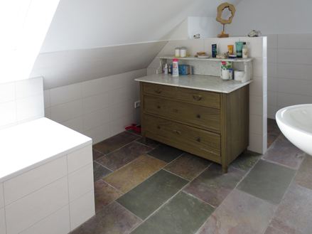 Barevná břidlice v koupelně skvěle doplňuje bílý interiér.