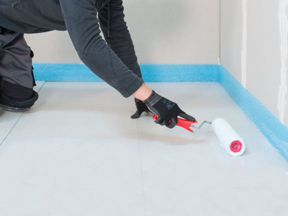 Obkladač nanáší základní nátěr válečkem